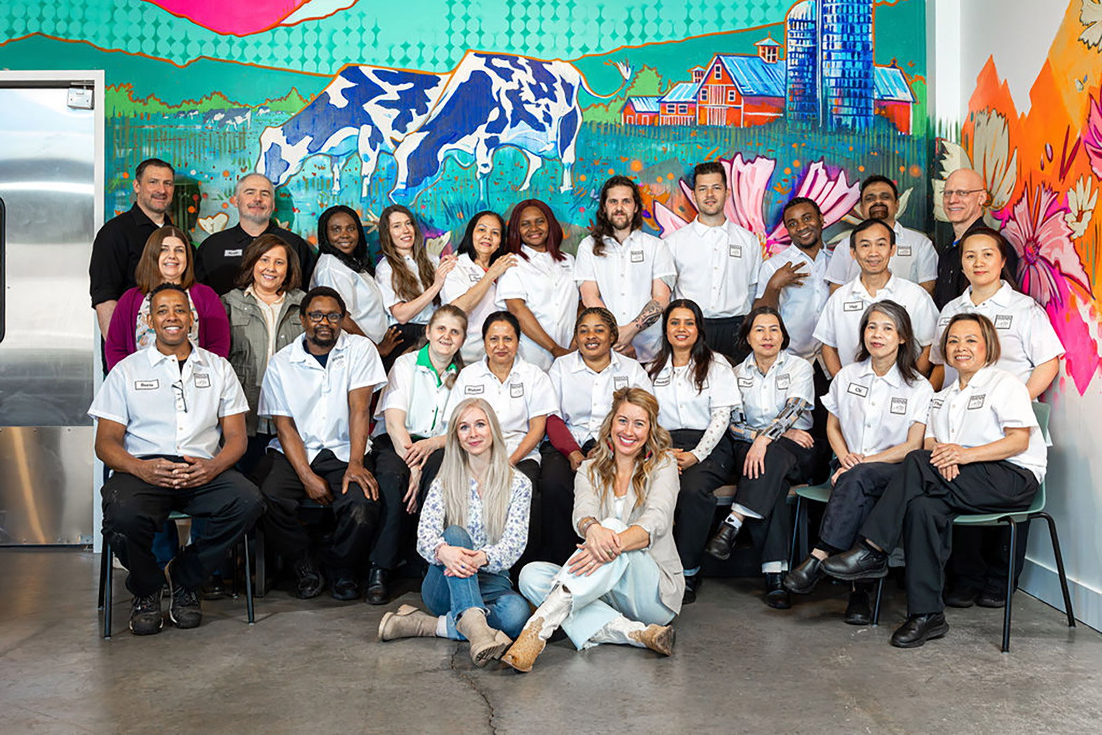 A large group photo of the Birnn Chocolates staff and team members sitting and standing together in matching white shirts.